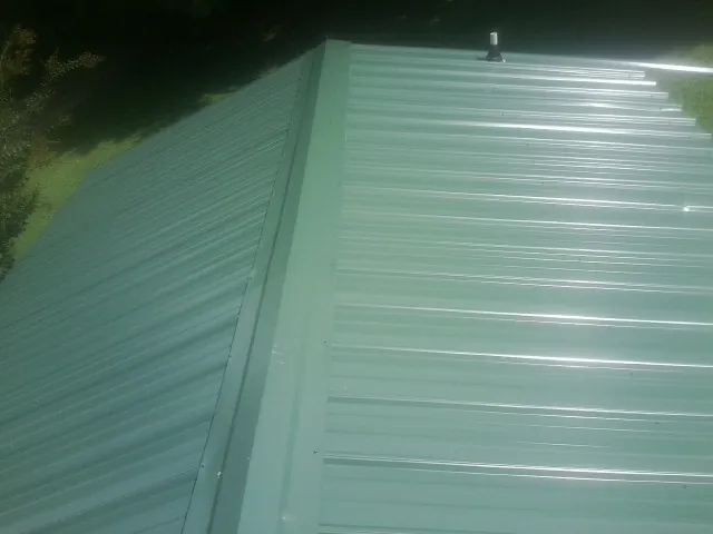 New green metal panels meeting at the ridge of a roof — Flat Roof Repair work by our crew in Touchet