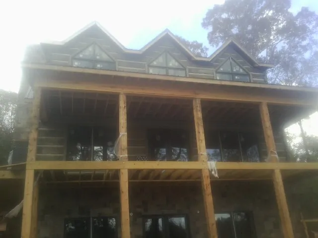 Dormers and porch framing on a large log home under construction — Roof Coating work by our crew in Touchet
