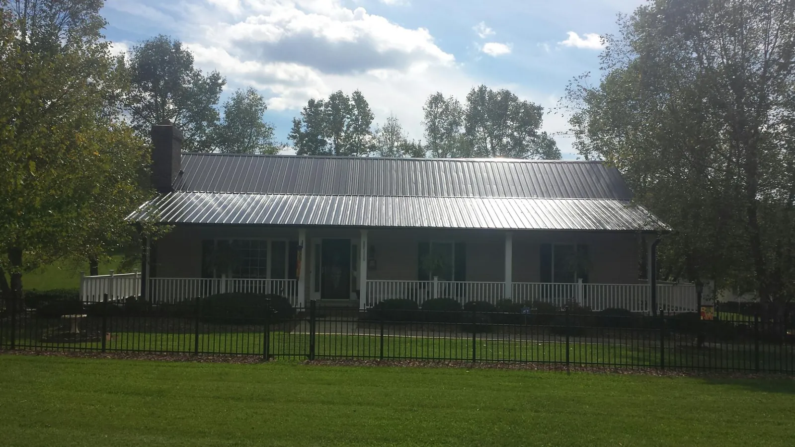 Gray metal roof on a brick ranch with a full width front porch — Gutter Guard Installation work by our crew in Touchet