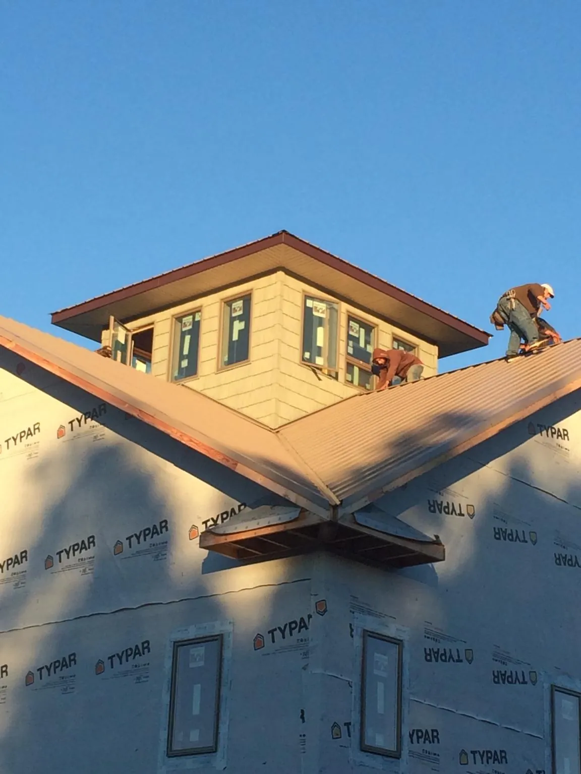 Roofers working around a rooftop cupola on a new metal roof at sunset — Roof Waterproofing in Touchet by Roofing Brothers